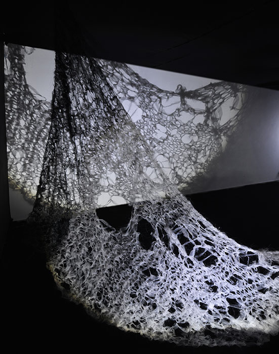 Abstract image of white cobweb looking object over a screen in a dark room