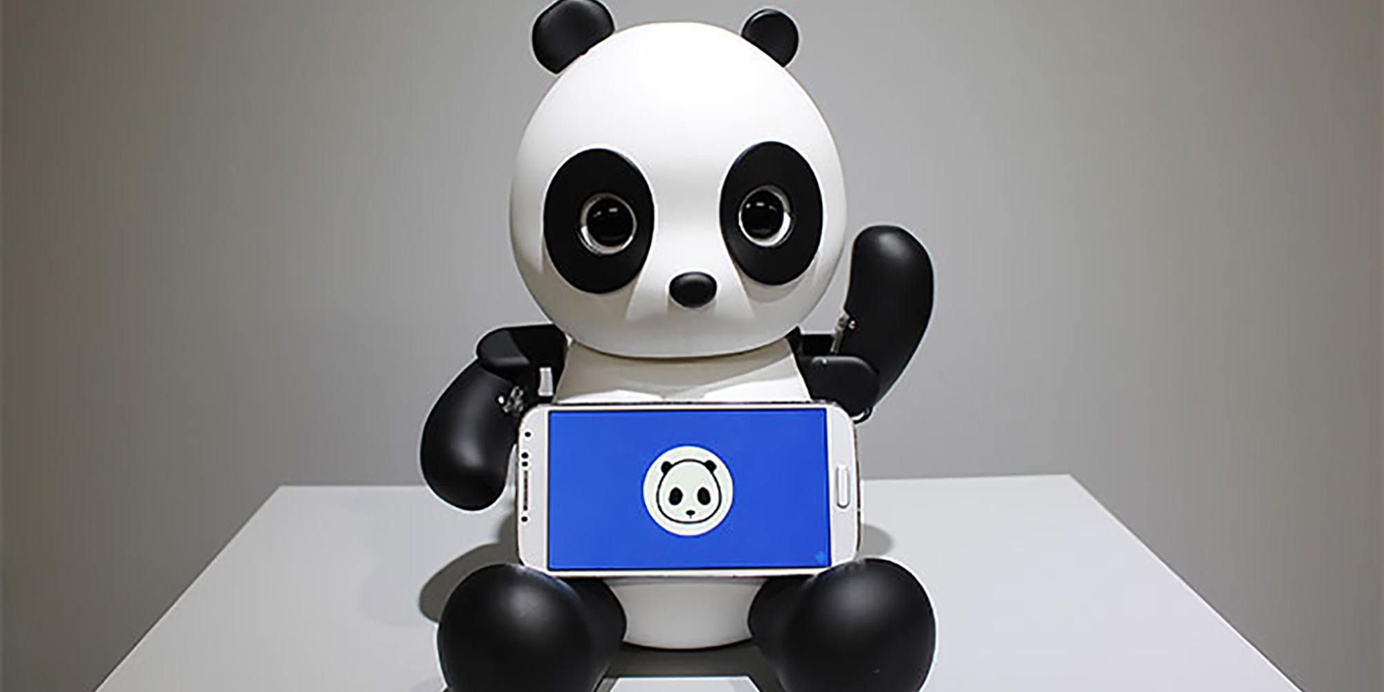 Black and white panda robot with mobile phone in his lap