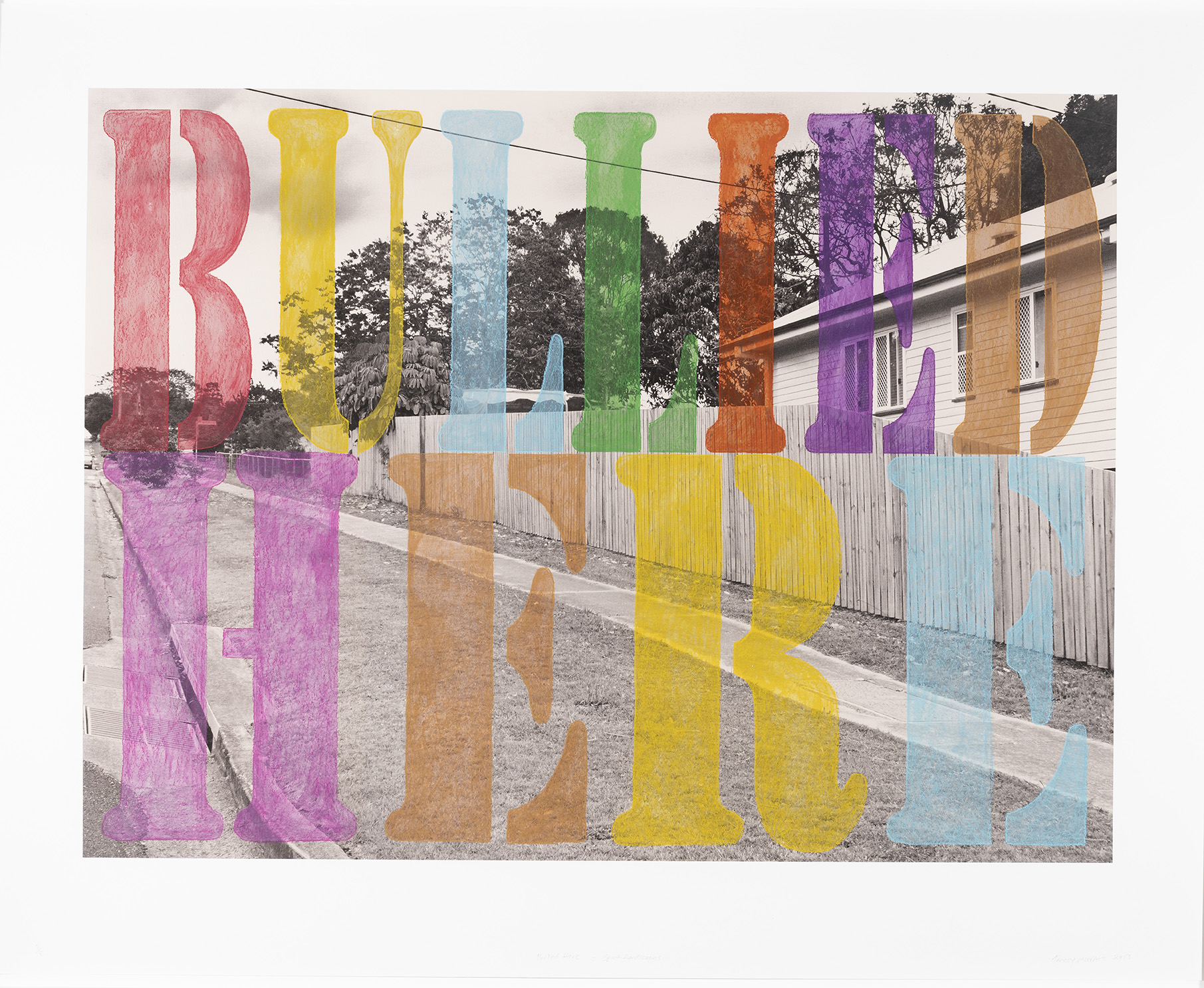 A black and white photograph of surburbia with the words 'Bullied here' in coloured wax crayon