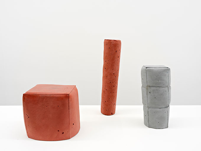 Print of group of three concrete objects (two red and one grey) in a room