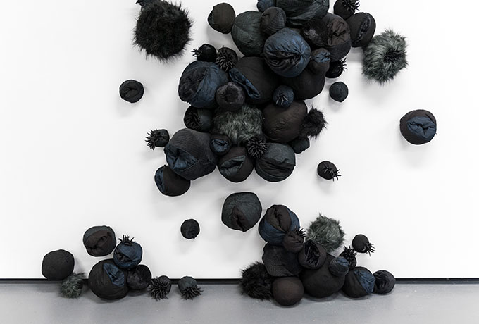 Abstract image of black balloons on the ground and hanging on the wall
