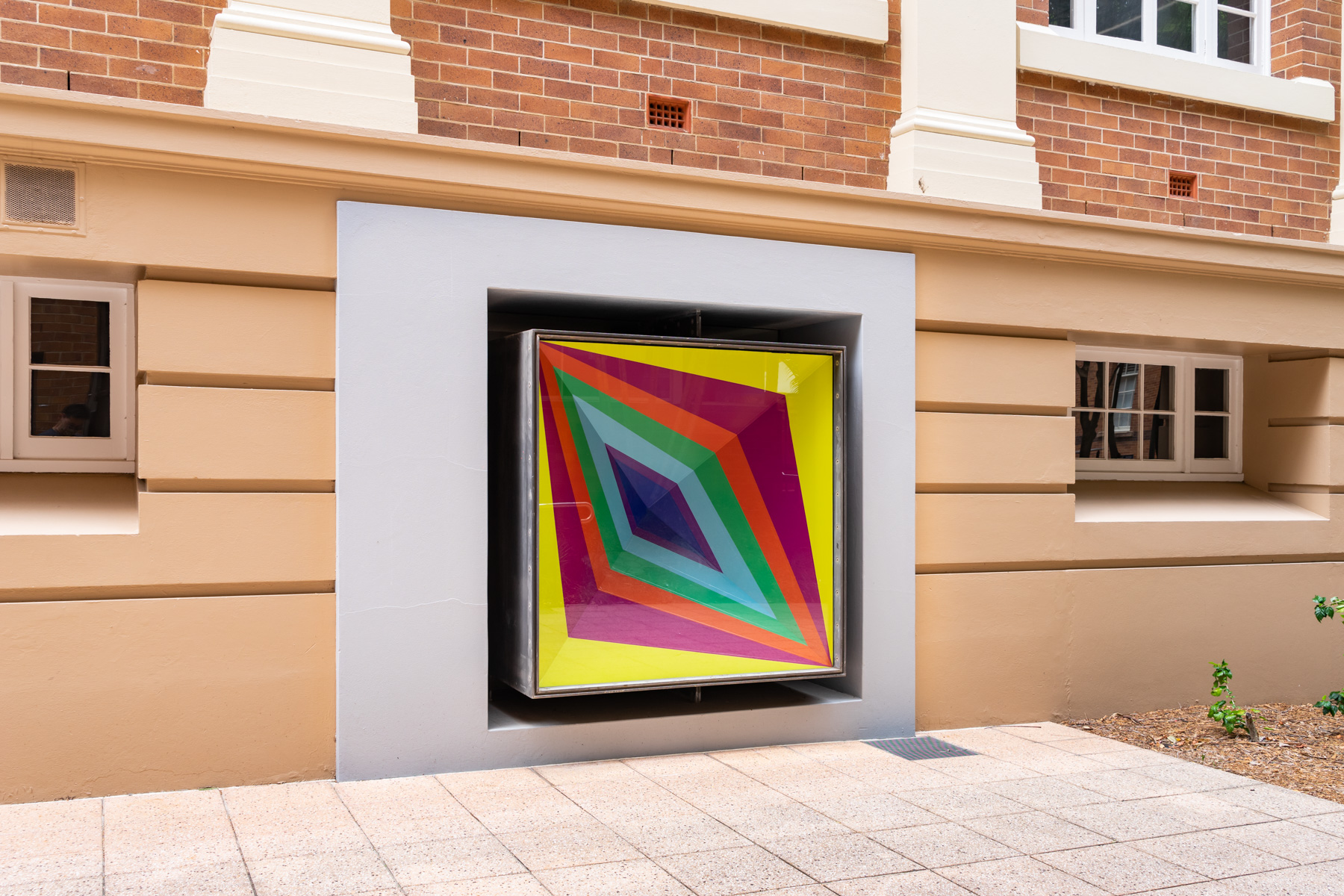 A building exterior with a colourful sculptural artwork installed in the window box