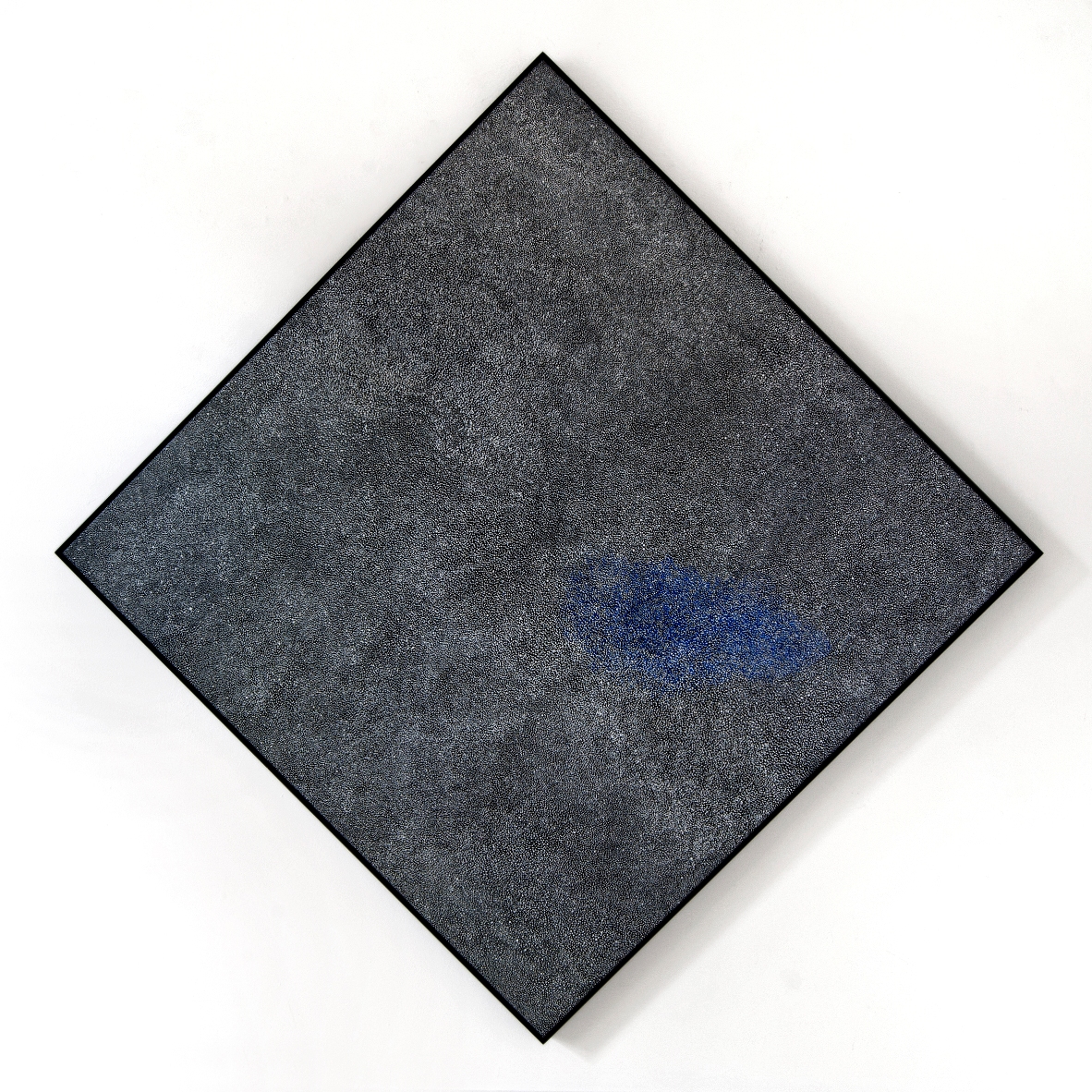 A framed square painting rotated 45 degrees so its corners point straight up, down, left and right. The painting is made up of fine white dots on a mostly black background, like a view of a starry night sky. 