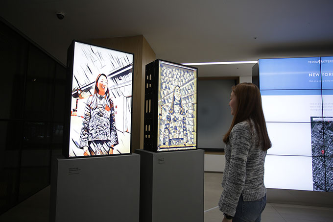 Image of woman looking at her reflection in a mirror installation in a gallery