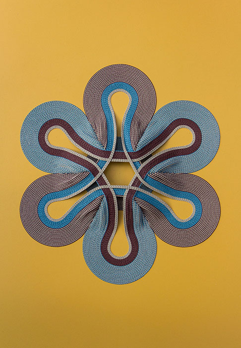 Image of blue and maroon fabric in circular formation on mustard yellow background