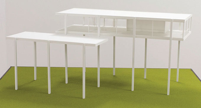 Image of two white structures – one rectangular table with tall legs, one rectangular house with tall legs 