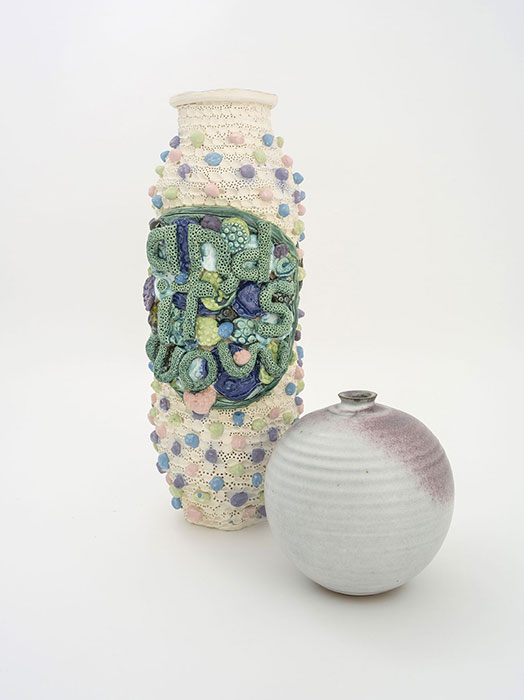 Image of two vases – one tall with multi-colour stones and decorative letters; one small grey vase