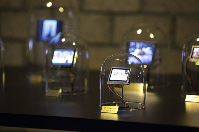Image of five mini computer monitors sitting on a black table, each computer is surrounded by a glass dome